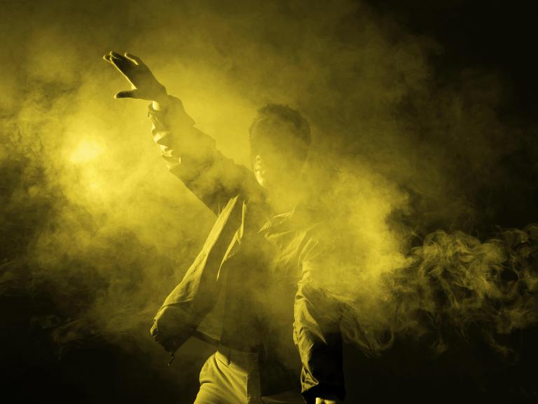Ein junger Mann tanzt in einem verrauchten Club mit leuchtendem Licht