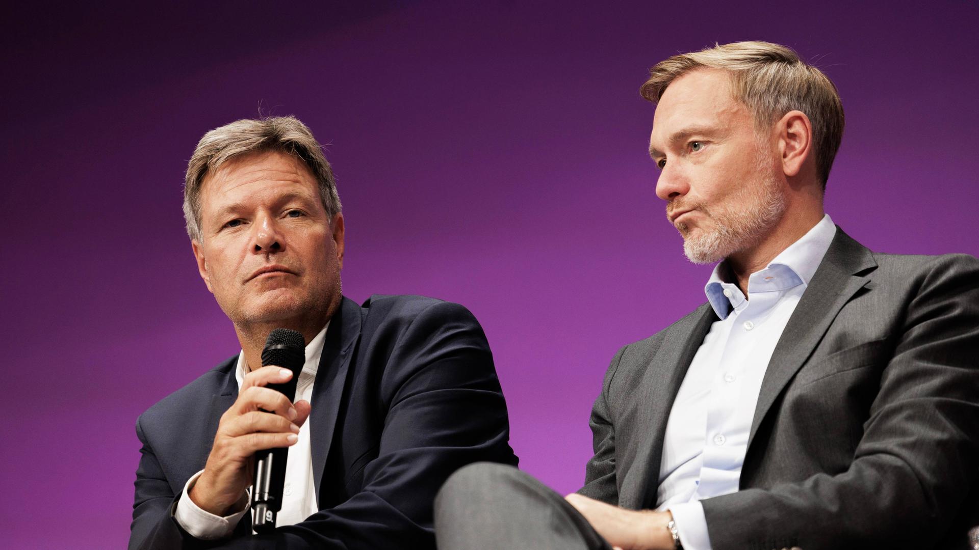 Wirtschaftsminister Robert Habeck (Bündnis 90/Die Grünen) und Finanzminister Christian Lindner (FDP) sitzen auf einen Podium. 