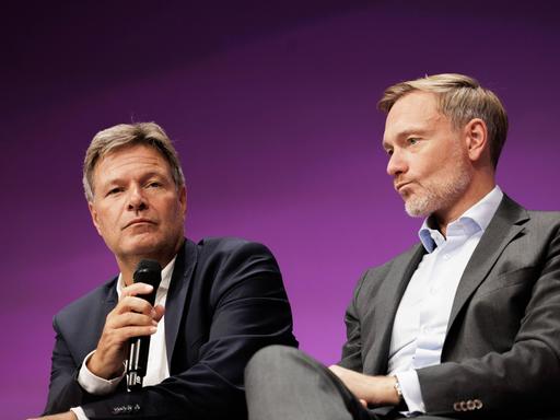 Wirtschaftsminister Robert Habeck (Bündnis 90/Die Grünen) und Finanzminister Christian Lindner (FDP) sitzen auf einen Podium. 