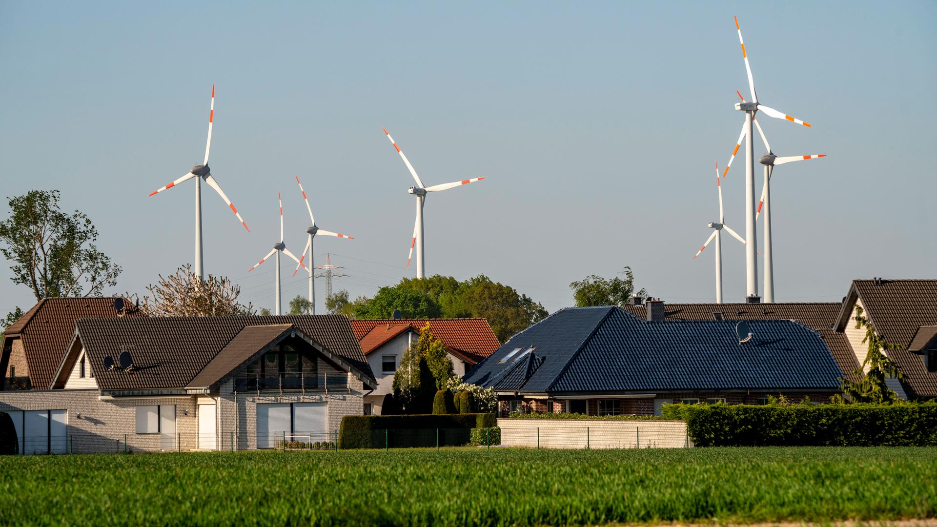 Eine Windkraftanlage steht in der Nähe eines Wohngebiets aus Einfamilienhäusern. Eine Windkraftanlage steht in der Nähe eines Wohngebiets aus Einfamilienhäusern.