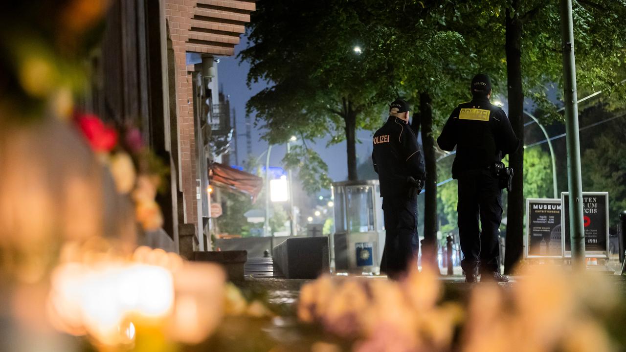Polizisten stehen vor der Neuen Synagoge an der Oranienburger Straße im Berliner Ortsteil Mitte. Im Vordergrund liegen Blumen und Kerzen.