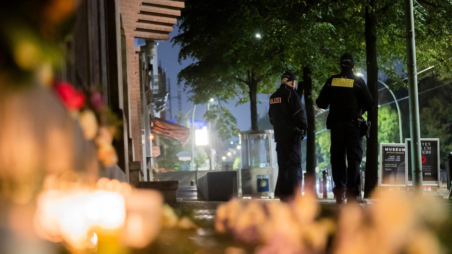 Polizisten stehen vor der Neuen Synagoge an der Oranienburger Straße im Berliner Ortsteil Mitte. Im Vordergrund liegen Blumen und Kerzen.
