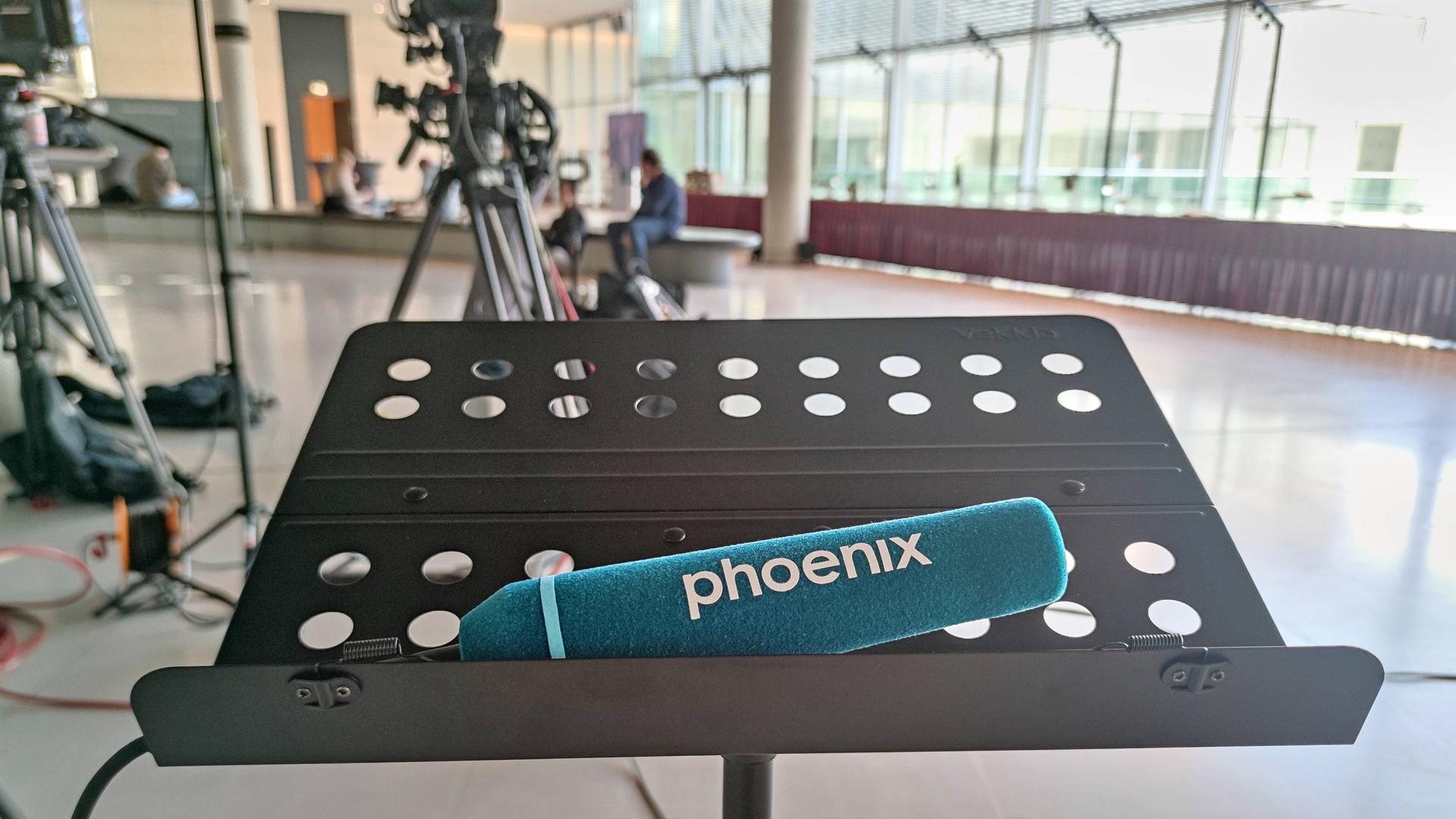 Ein Mikrophon des TV-Senders Phoenix liegt auf einem Dokumentenständer im Deutschen Bundestag. Ein Mikrophon des TV-Senders Phoenix liegt auf einem Dokumentenständer im Deutschen Bundestag.
