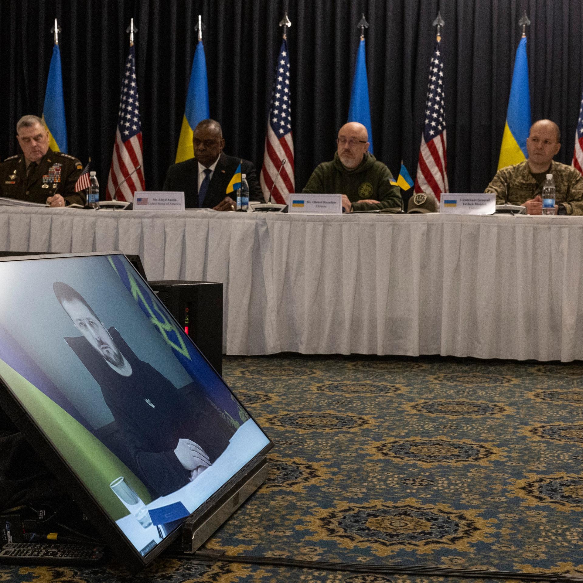 Der ukrainische Präsident Selenskyj spricht per Video über einen Bildschirm zu den Teilnehmern der Konferenz. Im Hintergrund der deutsche Verteidigungsminister Boris Pistorius (v.l.n.r.), der US-General Mark Milley, der amerikanische Verteidigungsminister Lloyd Austin, der ukrainische Verteidigungsminister Olexij Resnikow und der ukrainische General Jewgeni Moisjuk mit Übersetzerin. Der ukrainische Präsident Selenskyj spricht per Video über einen Bildschirm zu den Teilnehmern der Konferenz. Im Hintergrund der deutsche Verteidigungsminister Boris Pistorius (v.l.n.r.), der US-General Mark Milley, der amerikanische Verteidigungsminister Lloyd Austin, der ukrainische Verteidigungsminister Olexij Resnikow und der ukrainische General Jewgeni Moisjuk mit Übersetzerin.