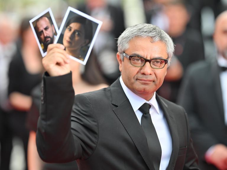 Der iranische Regisseur Mohammad Rasoulof hält Fotos seiner Hauptdarsteller Soheila Golestani und Missagh Zareh während der Vorführung des Films „The Seed Of The Sacred Fig“ bei den 77. jährlichen Filmfestspielen von Cannes im Palais des Festivals am 24. Mai 2024 hoch. 