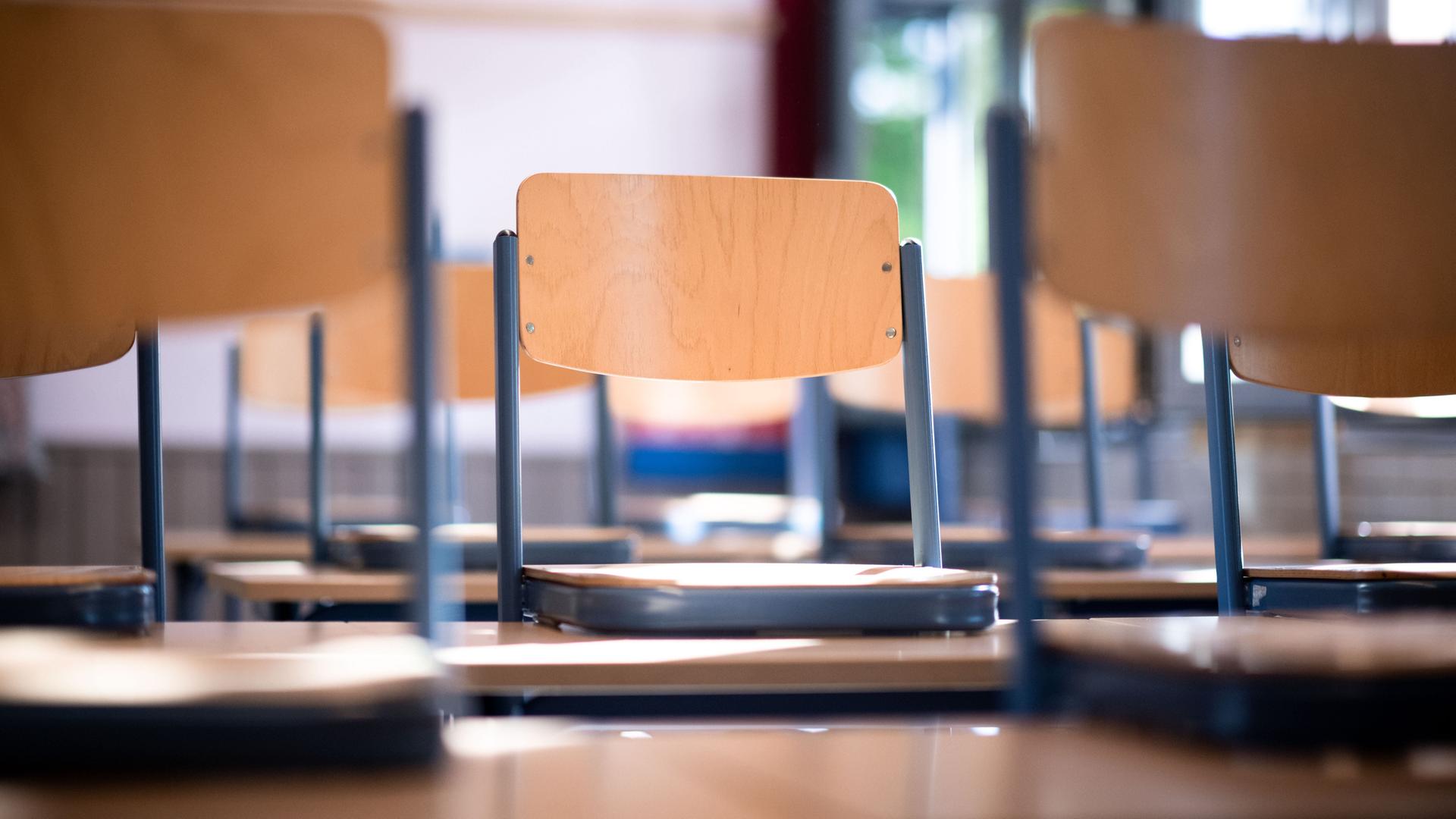 Stühle stehen auf Tischen in einem Klassenraum. 