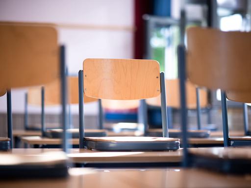 Stühle stehen auf Tischen in einem Klassenraum. 