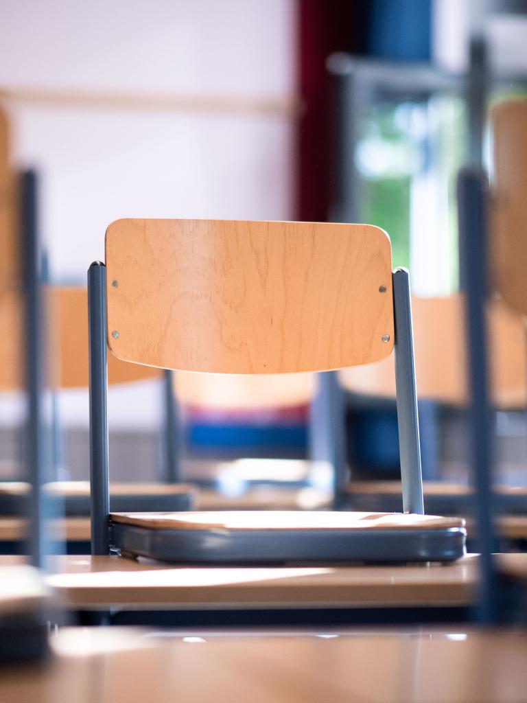 Stühle stehen auf Tischen in einem Klassenraum. 