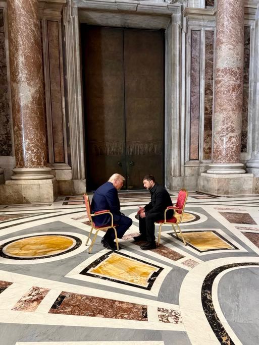Der ukrainische Staatschef Wolodymyr Selenskyj und US-Präsident Donald Trump sitzen im Petersdom auf Stühlen und unterhalten sich.