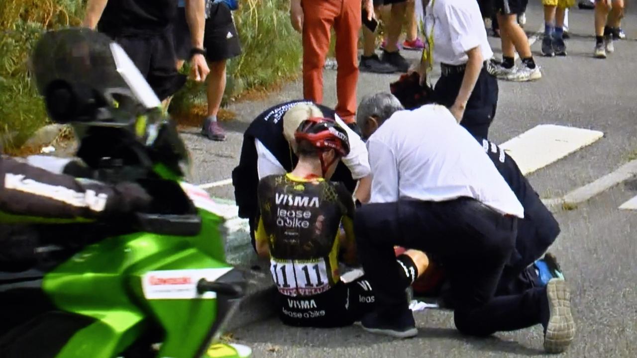 Zwei Männer kümmern sich um Jonas Vingegaard, der nach einem Sturz bei der Tour de France verletzt auf der Straße sitzt.