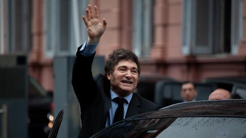 Der argentinische Präsident Javier Milei winkt in Richtung Kameras beim Einsteigen in ein Auto. Buenos Aires, Argentinien, 2024.