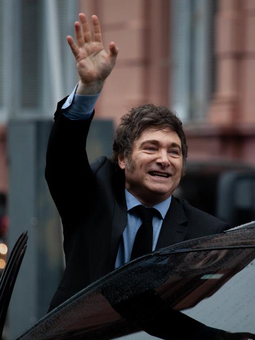 Der argentinische Präsident Javier Milei winkt in Richtung Kameras beim Einsteigen in ein Auto. Buenos Aires, Argentinien, 2024.