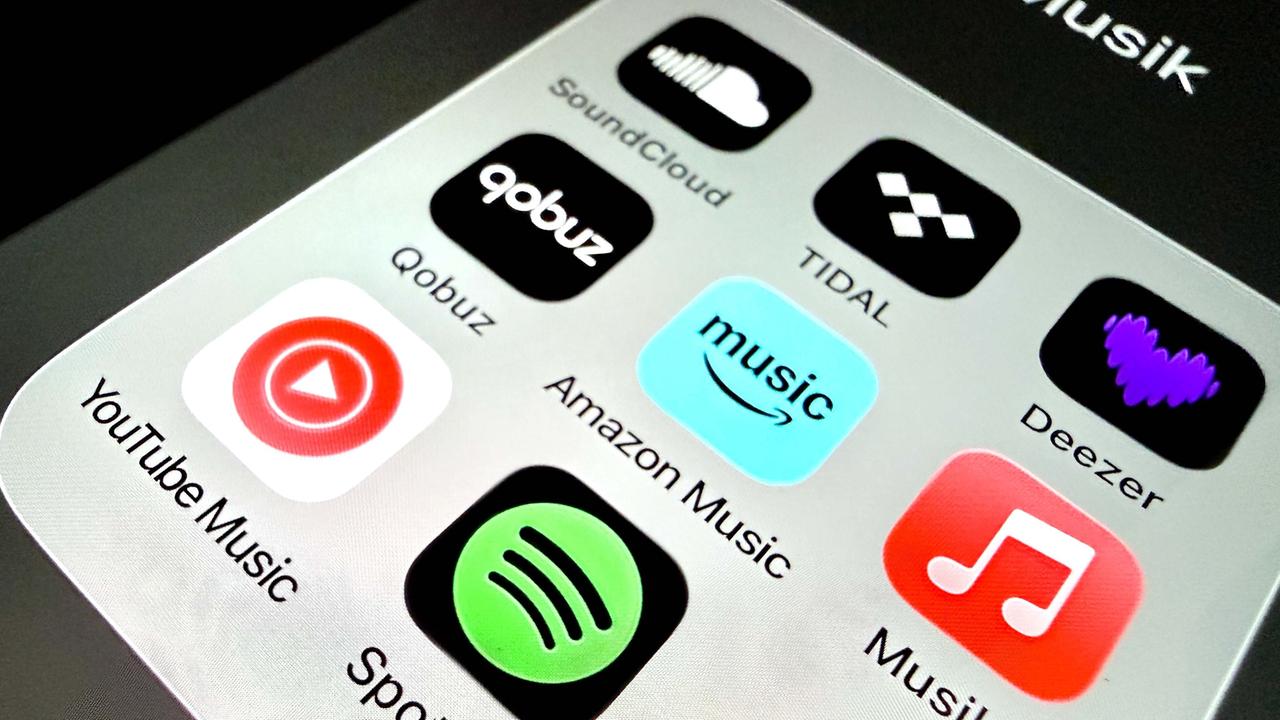 Auf einem Handydisplay sind Apps verschiedener Musikstreamingplattformen zu sehen.
