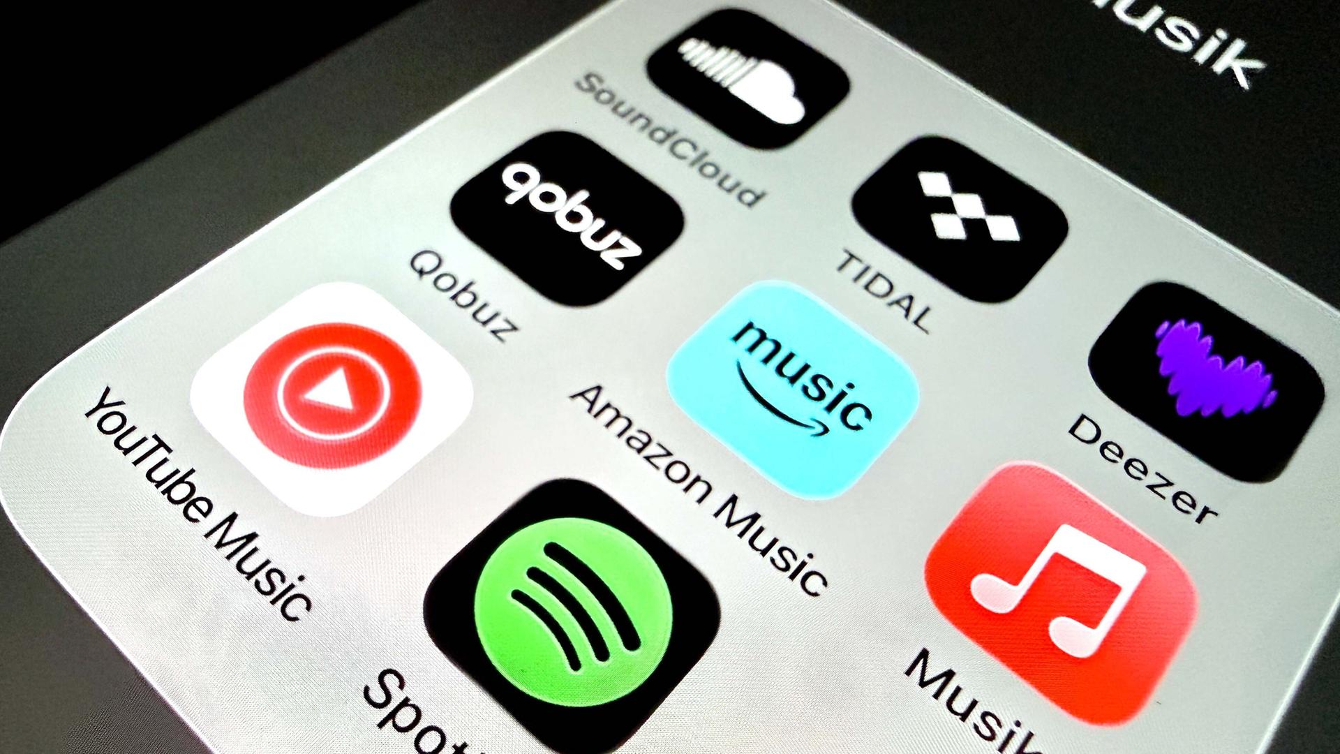 Auf einem Handydisplay sind Apps verschiedener Musikstreamingplattformen zu sehen.