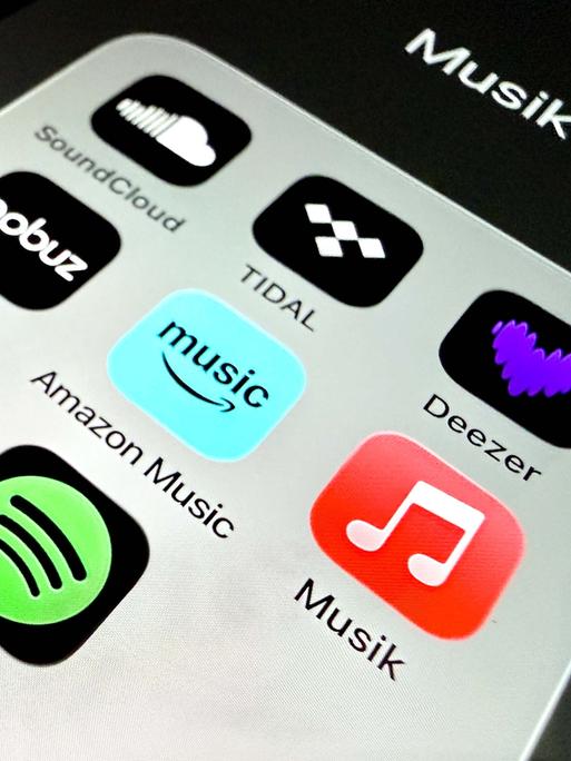 Auf einem Handydisplay sind Apps verschiedener Musikstreamingplattformen zu sehen.