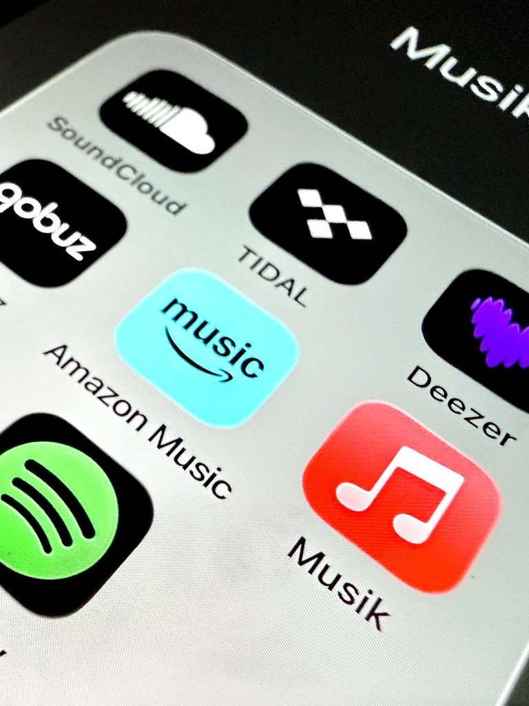 Auf einem Handydisplay sind Apps verschiedener Musikstreamingplattformen zu sehen.