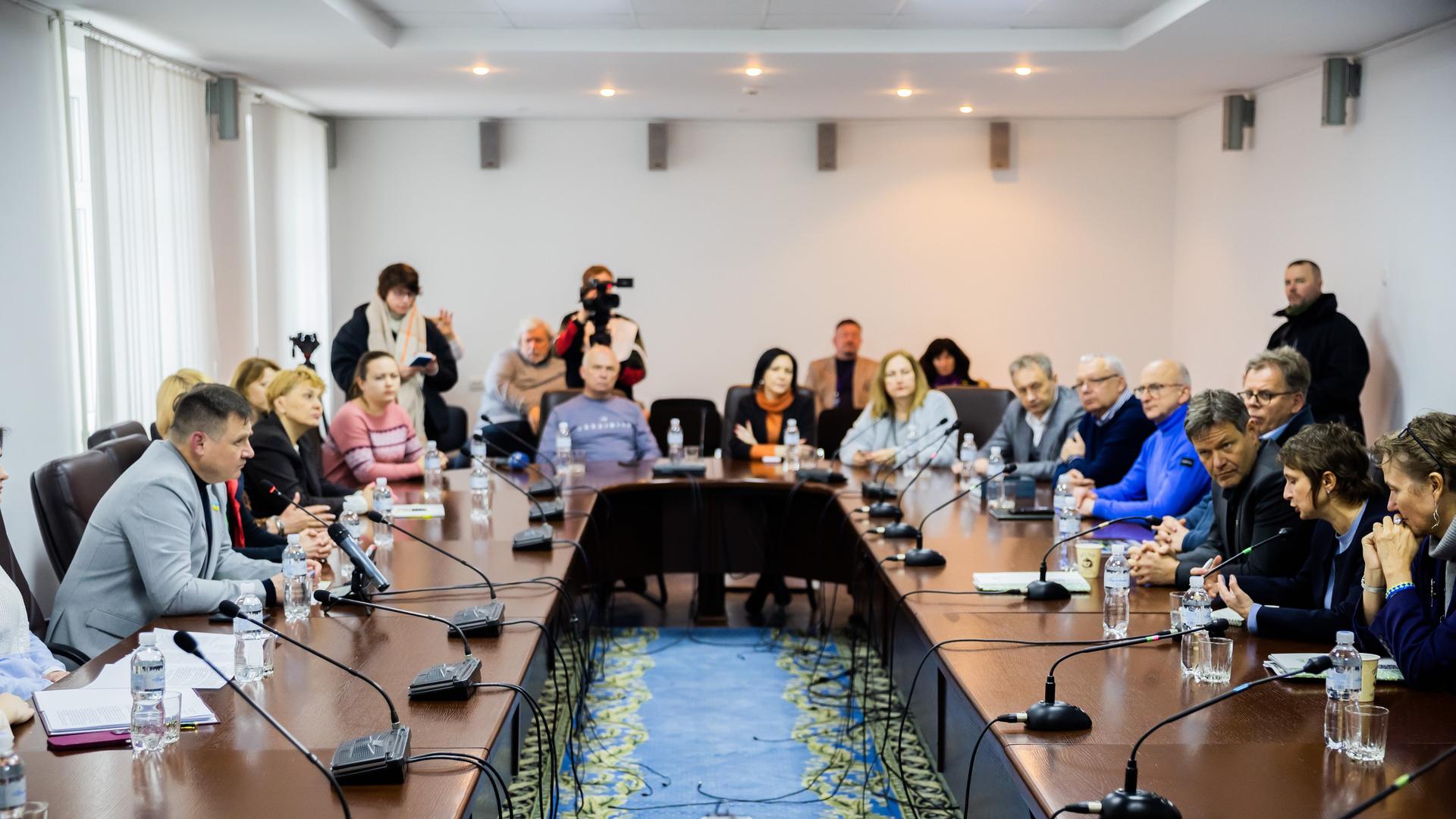 Ukraine, Slawutytsch: Bundeswirtschaftsminister Habeck mit Jurij Fomitschow (l), Bürgermeister der Gemeinde Slawutytsch und Mitarbeitern zusammen an einem Tisch. Vor ihnen stehen Mikrofone.