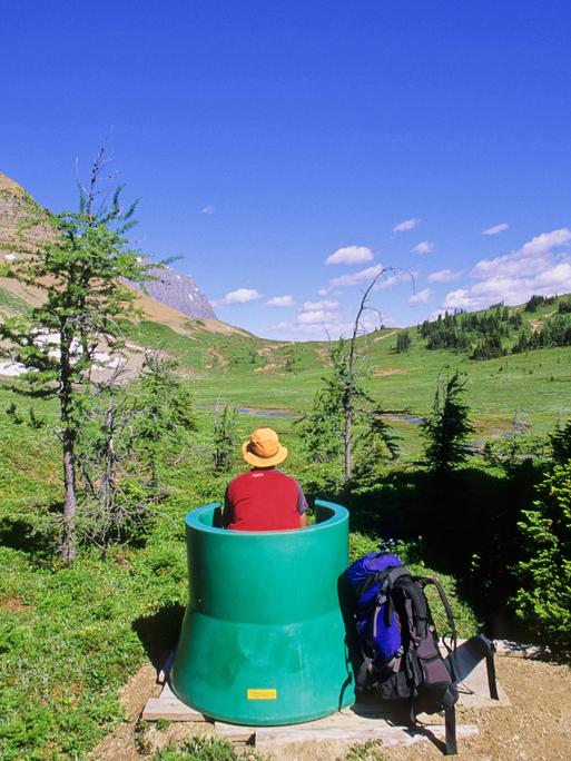 Eine Person bei einer Pinkelpause in einem grünen Fass in Kanada.