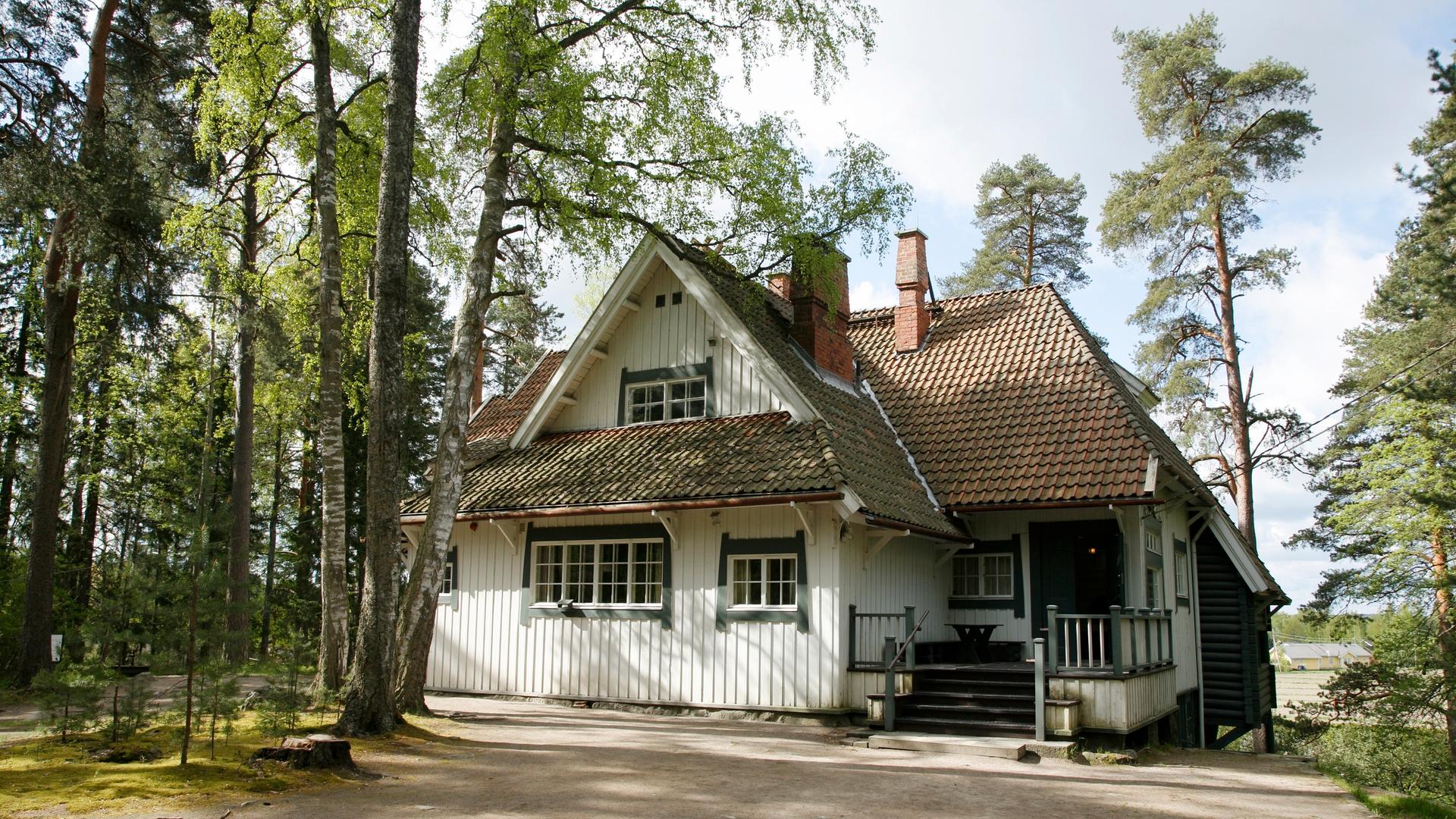 Blick auf das weiß angestrichene Holzhaus von Jean Sibelius, das von Birken umgeben ist.