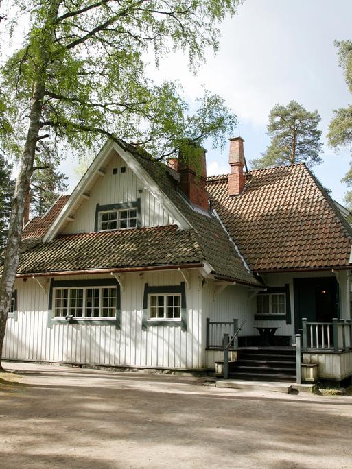 Blick auf das weiß angestrichene Holzhaus von Jean Sibelius, das von Birken umgeben ist.