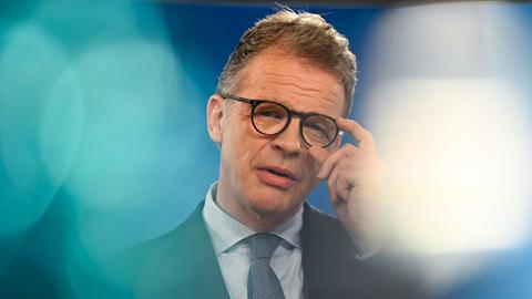 Christian Sewing, Vorsitzender des Vorstands der Deutschen Bank, spricht. Mit seiner linken Hand fasst er sich an die Brille.