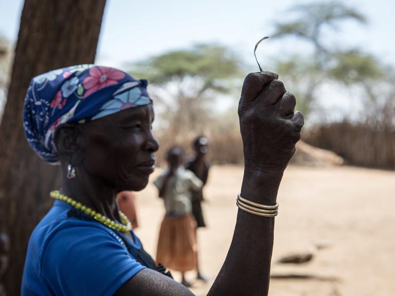 Eine Aufnahme aus dem Jahr 2018 zeigt eine Frau in einem Dorf in Uganda, die nach eigener Aussage die „Vorsitzende der Messerschneider“ in ihrem Stamm gewesen ist, bevor die weibliche Genitalverstümmelung (FGM) 2010 in Uganda verboten wurde. Sie zeigt das Werkzeug, mit dem sie junge Mädchen beschnitten hat. 