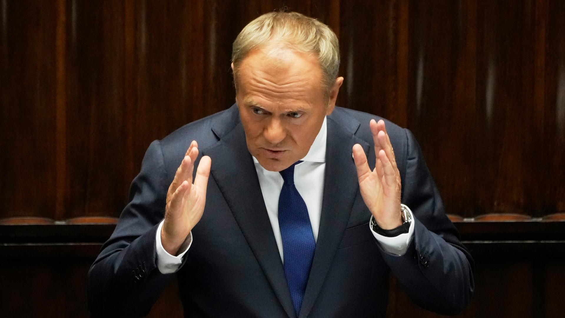 Polens Premierminister Donald Tusk steht an einem Rednerpult und gestikuliert. 