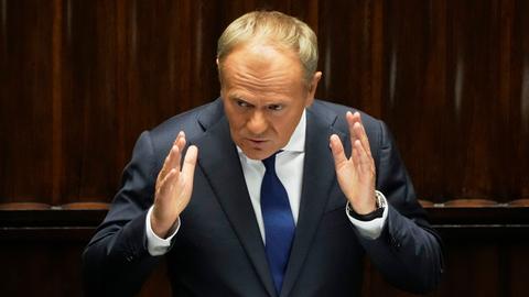Polens Premierminister Donald Tusk steht an einem Rednerpult und gestikuliert. 