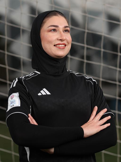 Mursal Sadat von der "Afghan Woman United" Fussballmannschaft posiert vor einem Tornetz. Sie trägt schwarze Spielkleiderung. 