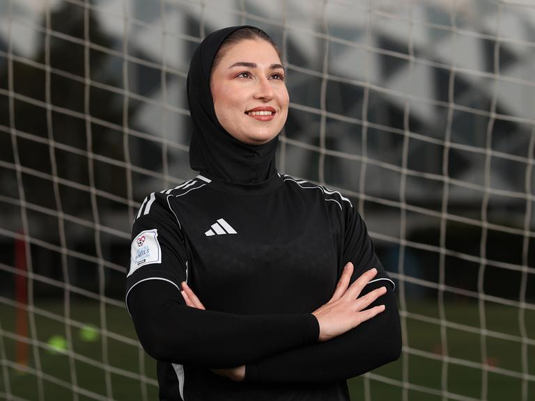 Mursal Sadat von der "Afghan Woman United" Fussballmannschaft posiert vor einem Tornetz. Sie trägt schwarze Spielkleiderung. 