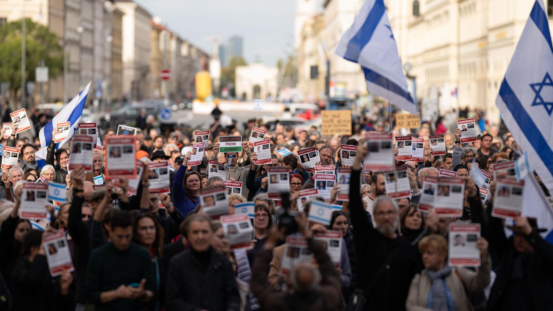 Teilnehmer der Kundgebung "Solidarität mit Israel - Gegen gegen Terror, Hass und Antisemitismus" halten Flugblätter mit der Aufschrift "Entführt" in die Höhe.