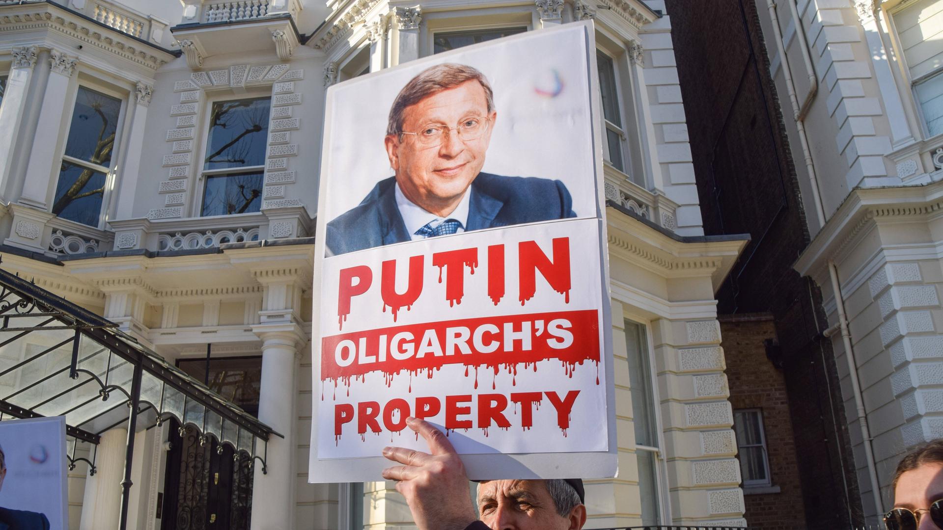 Ein Demonstrant in London hält ein Plakat hoch, dass den russischen Oligarchen Wladimir Jewtuschenkow zeigt. 