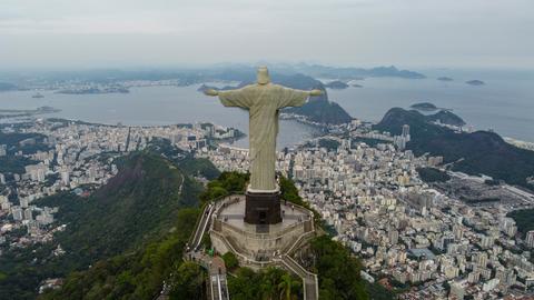 Eine Luftaufnahme zeigt die Stadt Rio De Janeiro umringt von grünen Wäldern und zu Füßen der großen Christus der Erlöser Statue liegend.