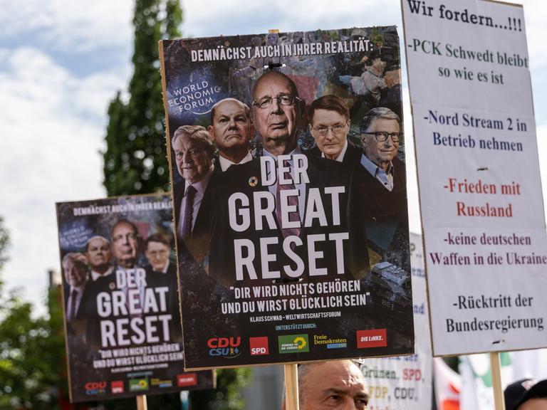 Ein Demonstrant hält ein Schild mit der Aufschrift "The Great Reset!", während er und andere Demonstranten sich versammeln, um ein Ende des geplanten deutschen Embargos gegen die Einfuhr von russischem Öl zu fordern.
