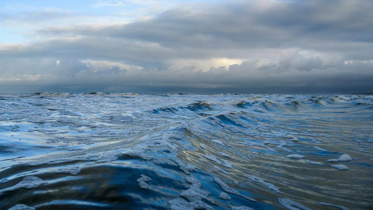 Dunkle Wellen schieben sich vor drohenden Regenwolken über die Nordsee.