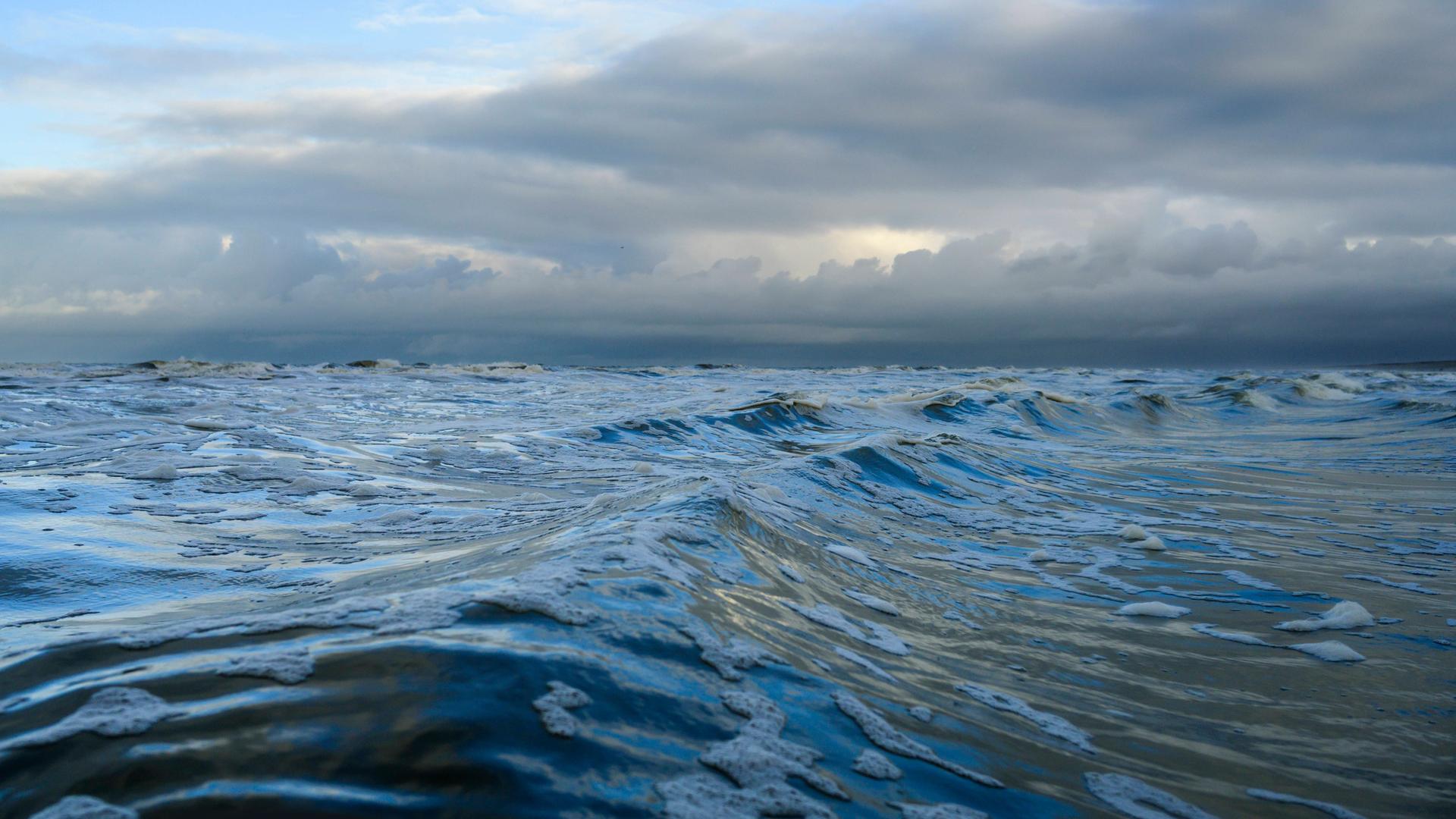 Dunkle Wellen schieben sich vor drohenden Regenwolken über die Nordsee.