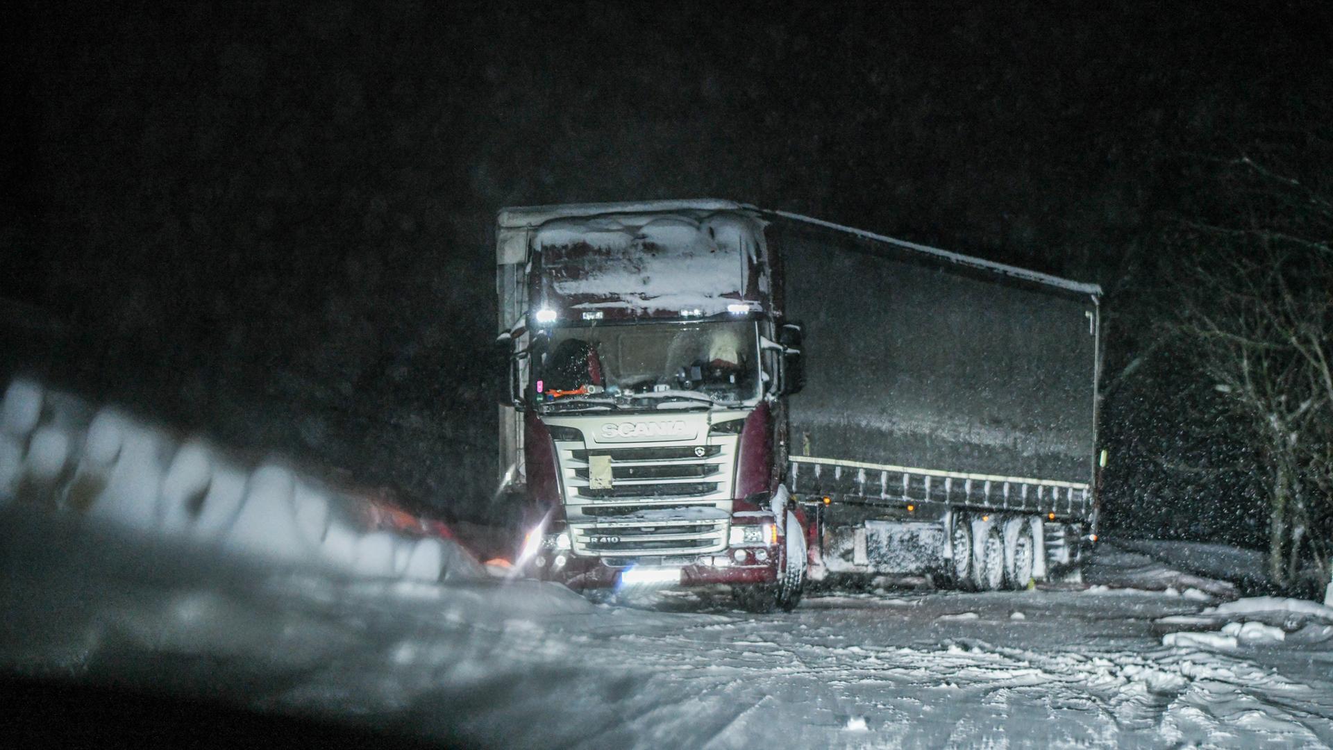 Ein Lkw steht in der Dunkelheit schräg im Schnee. 