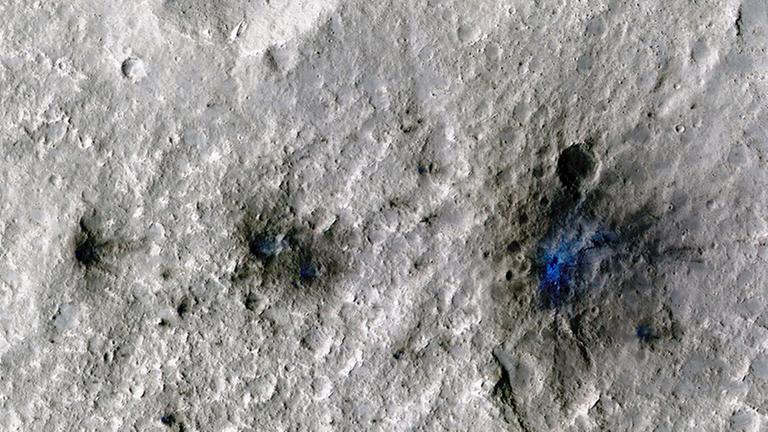 Dieses Foto zeigt Krater, die durch einen Meteoriteneinschlag auf dem Mars entstanden sind. Das Bild hebt den durch den Einschlag aufgewirbelten Staub und Boden in Blau hervor. Dieses Foto zeigt Krater, die durch einen Meteoriteneinschlag auf dem Mars entstanden sind. Das Bild hebt den durch den Einschlag aufgewirbelten Staub und Boden in Blau hervor.