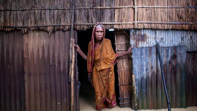 Eine ältere Frau steht am 6. Oktober 2024 vor ihrem Haus im knietiefen Hochwasser in einem Dorf im Jhenaigati Upazila des Bezirks Sherpur in Bangladesch. 