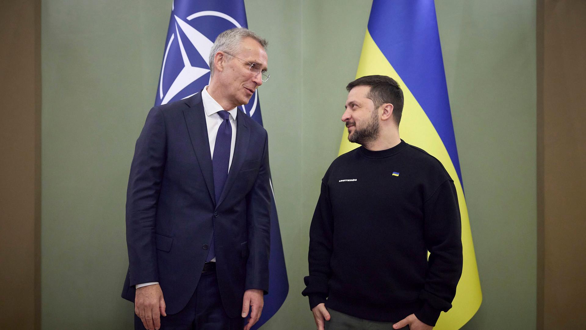 Nato-Generalsekretär Stoltenberg und der ukrainische Präsident Selenskyj stehen auf einer Bühne nebeneinander vor der Fahne der Nato und der Fahne der Ukraine.