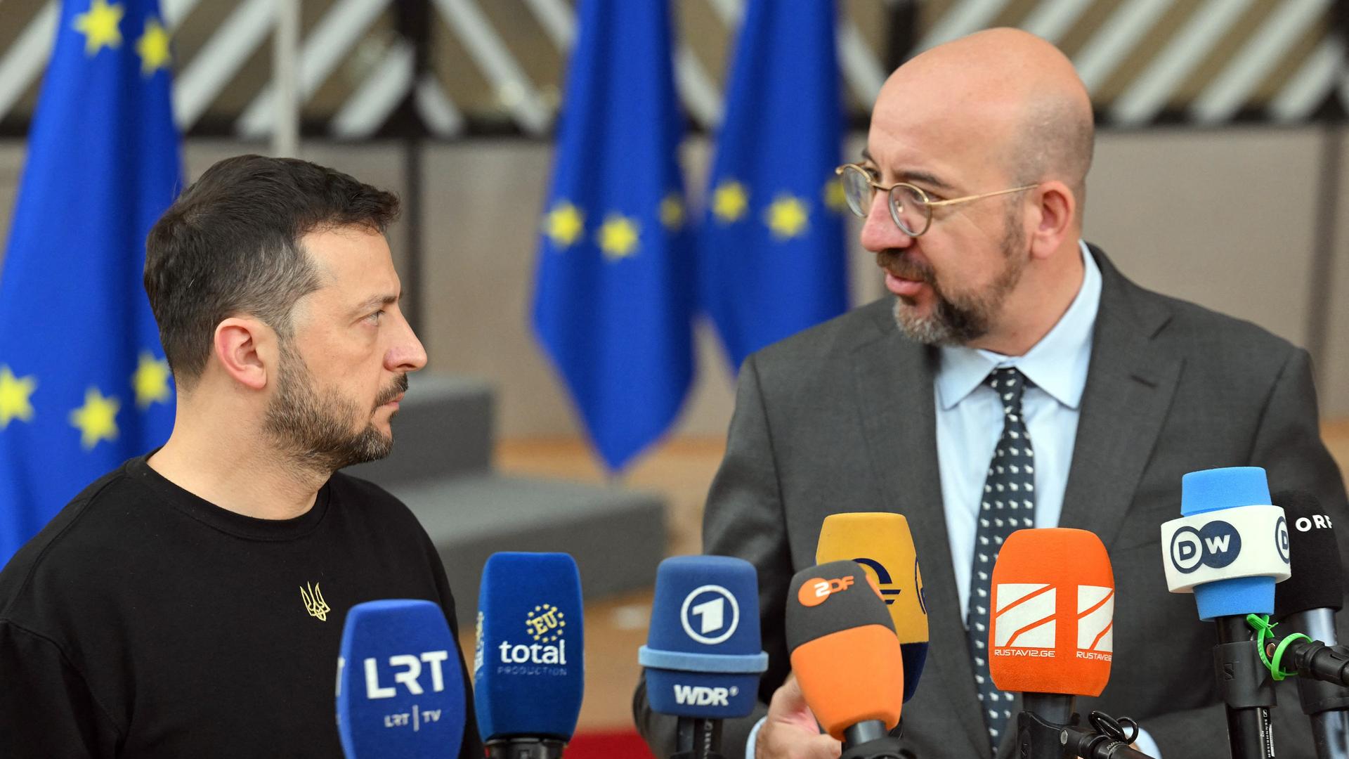 Die beiden stehen nebeneinander in einem Raum vor vielen Mikrofonen und schauen einander an. Michel sagte etwas. Dahinter unscharf mehrere EU-Flaggen. 