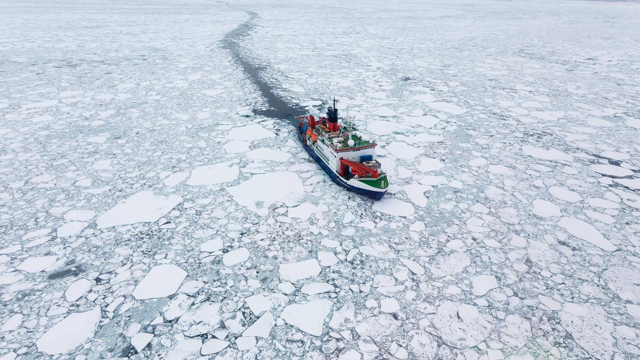 Das Forschungsschiff Polarstern fährt im arktischen Meer an großen Eisschollen vorbei.