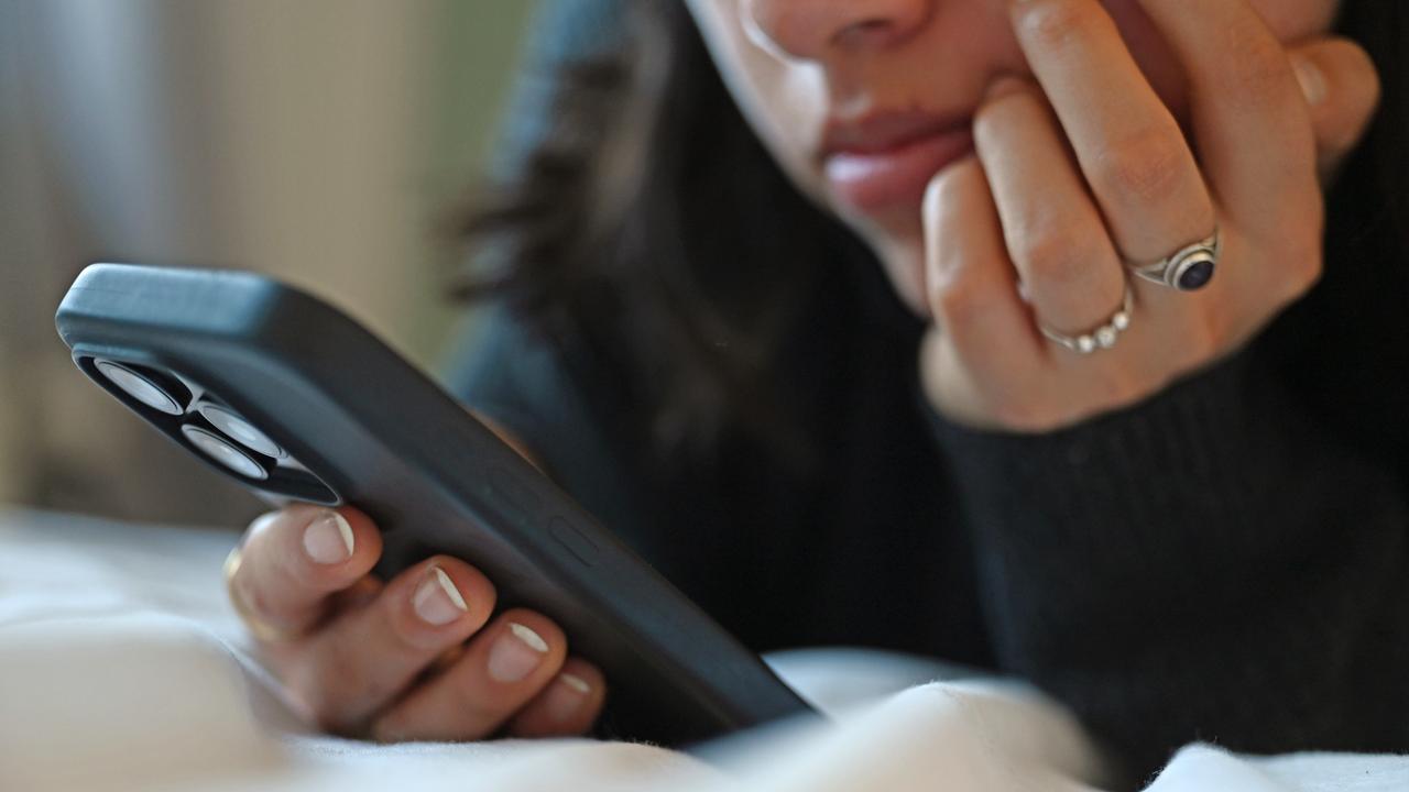 Eine junge Frau liegt mit dem Smartphone in der Hand auf dem Bett. Eine junge Frau liegt mit dem Smartphone in der Hand auf dem Bett.