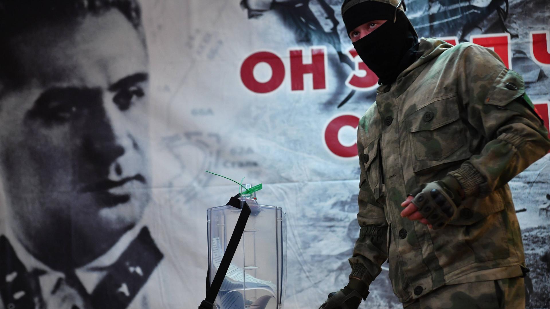 Scheinreferenden in russisch besetzten Gebieten in der Ukraine: Ein Uniformierter gibt seine Stimme in einem Wahllokal ab.