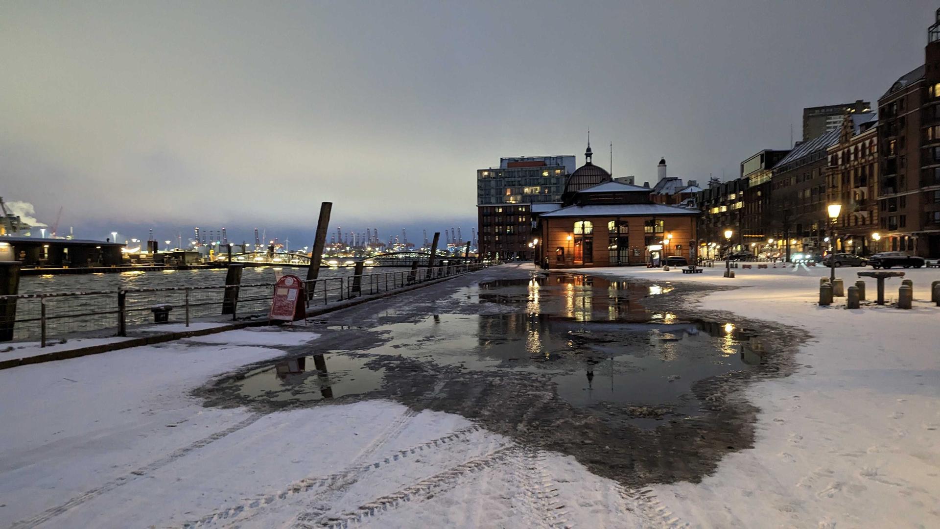 Ein Pfütze hat sich zwischen frischem Schnee am Fischmarkt in Hamburg gebildet.