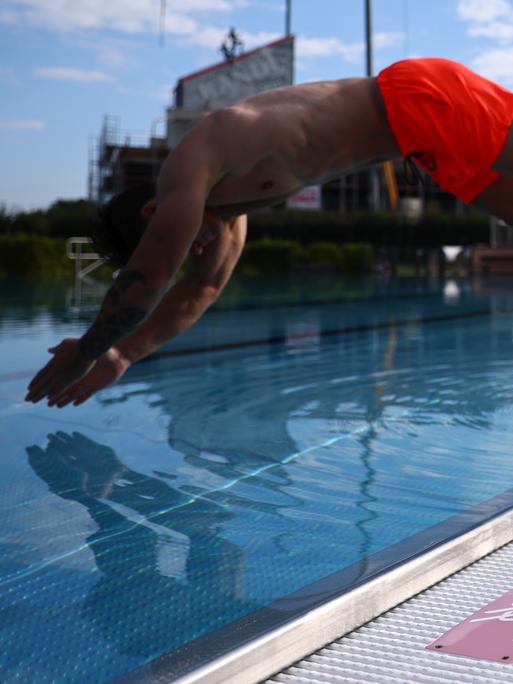 Ein Mann springt vom Beckenrand eines Freibades ins Schwimmbecken Symbolbild Freibad, Urlaub und Sommer Foto: Rene Weiss/Eibner