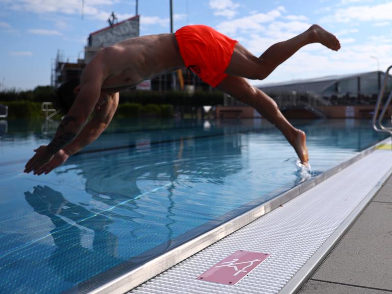 Ein Mann springt vom Beckenrand eines Freibades ins Schwimmbecken Symbolbild Freibad, Urlaub und Sommer Foto: Rene Weiss/Eibner