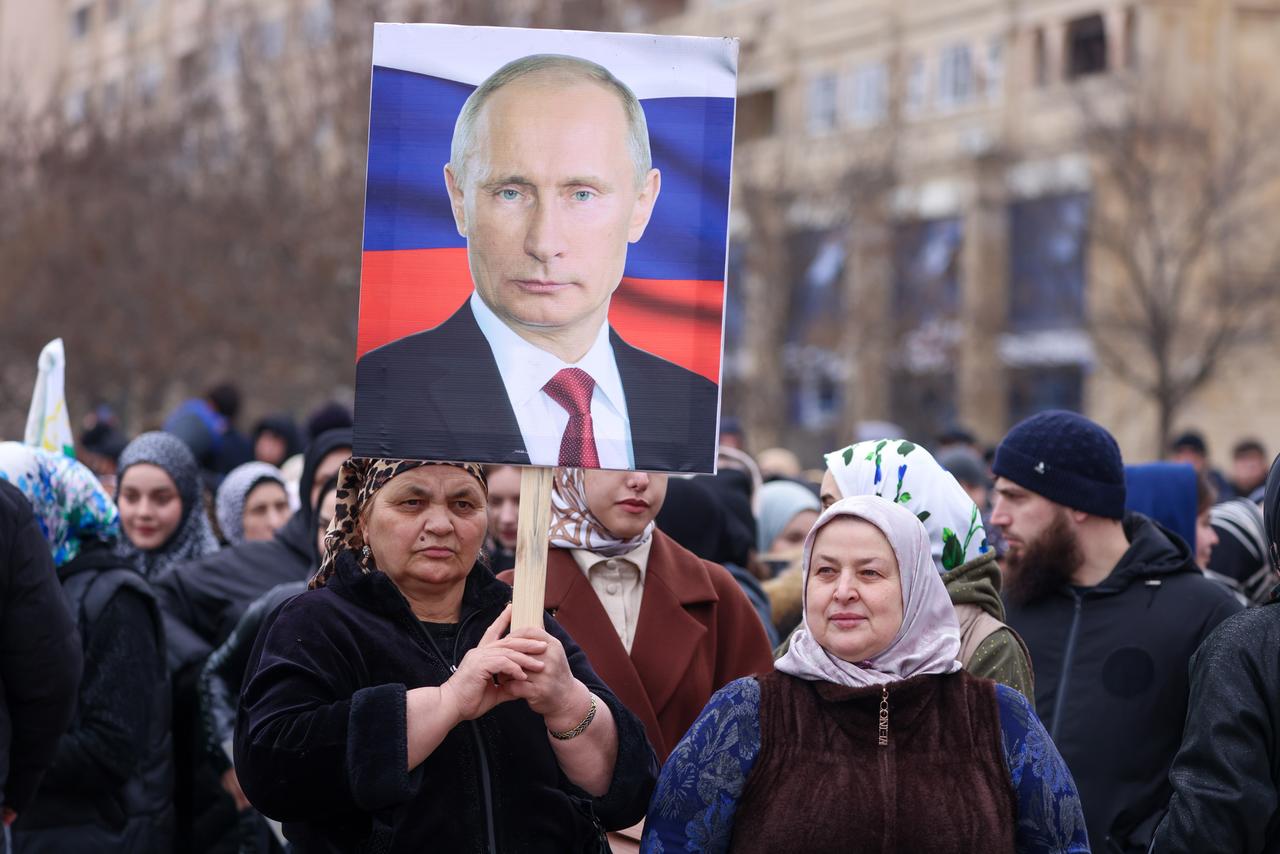 Anhänger von Wladimir Putin halten ein Plakat mit einem Porträt des russischen Präsidenten hoch.