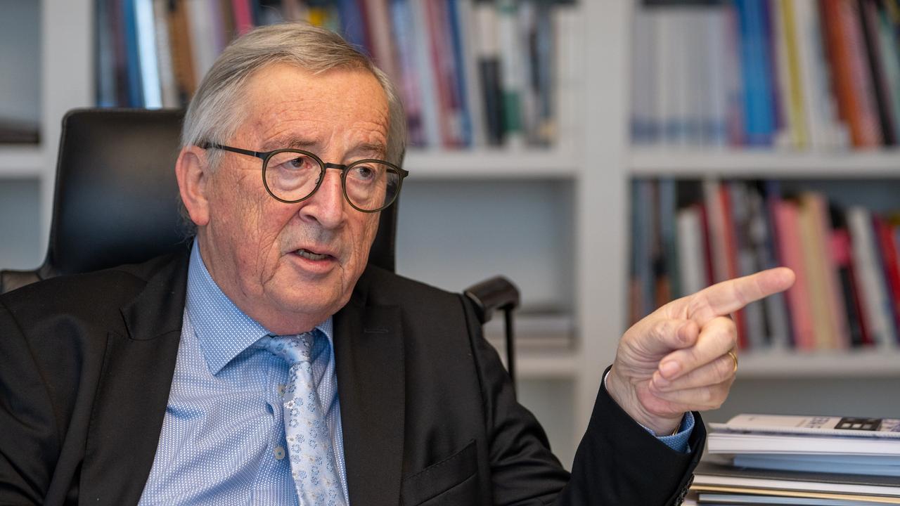 Jean-Claude Juncker, im Gespräch an seinem Schreibtisch, unterstreicht eine Aussage mit ausgestrecktem Zeigefinger.