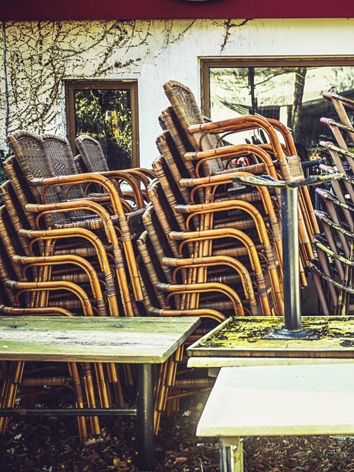 Gestapelte Stühle stehen draußen vor einem geschlossenen Restaurant.
